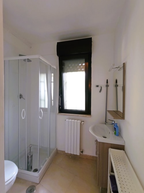 Bagno moderno della villa vacanze a Bari con box doccia in vetro, lavabo bianco, radiatore e finestra