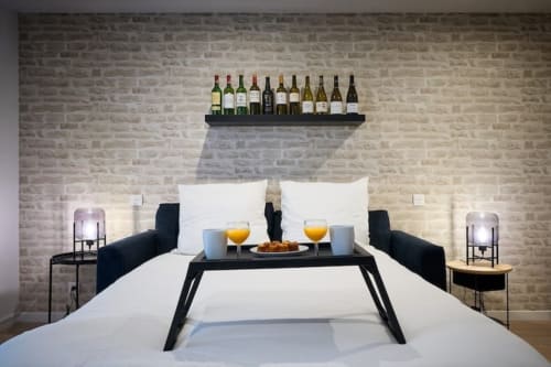 Modern studio apartment bedroom in Bordeaux with wine bottles on shelf, breakfast tray, and city view