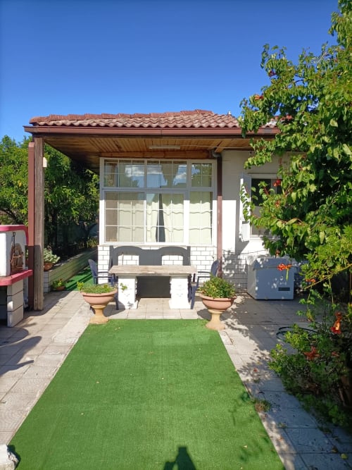 Villa Newhouse a Bari con prato curato, pergolato in legno, finestre con persiane bianche e rigogliosa edera rampicante