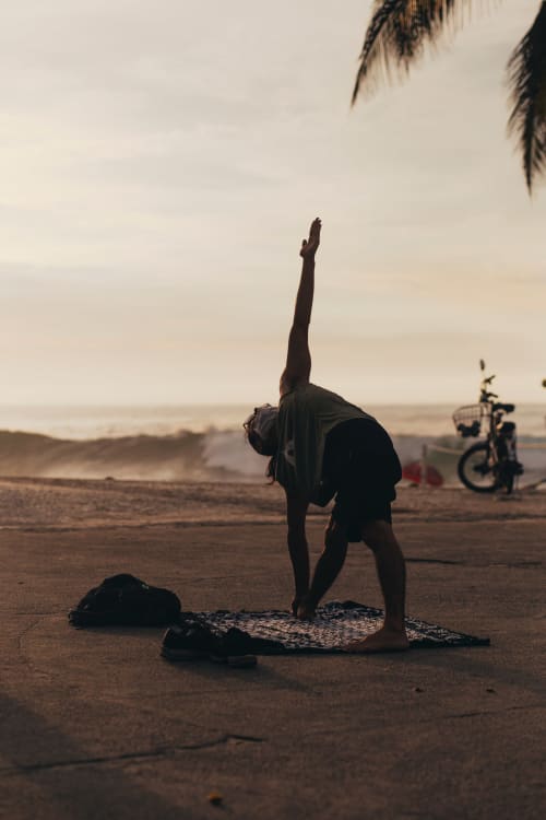 Pessoa praticando yoga na praia ao pôr do sol perto do Hostel New Ipanema no Rio de Janeiro