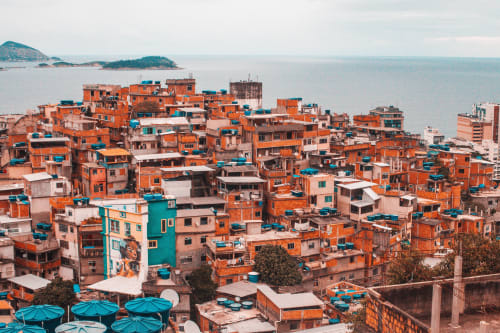 Edifícios coloridos em tons de laranja e azul-petróleo do bairro de hostels no Rio de Janeiro com oceano e ilhas ao fundo