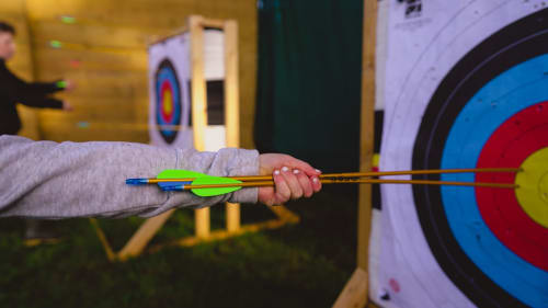 Person holding arrow aimed at colorful archery target at Sliabh Beagh Hotel & Tourism Centre in Monaghan, Ireland