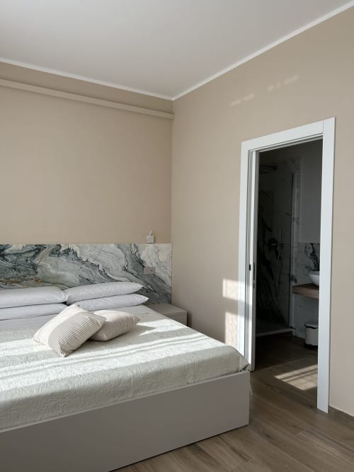 Camera luminosa e moderna a Breccia nel Mare B&B a Marina di Carrara con testiera in marmo, biancheria bianca e bagno ensuite