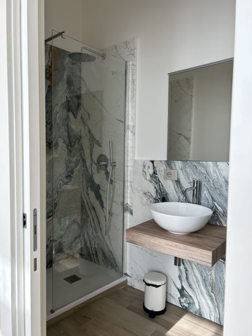 Bagno moderno a Breccia nel Mare con doccia in marmo, lavabo da appoggio e mobile in legno a Marina di Carrara