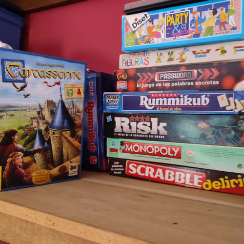 Colección de juegos de mesa apilados en estantería de madera en el hotel Casa Lafuente de Lukiano, España