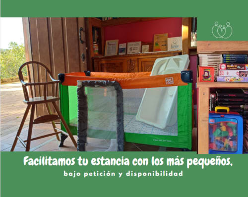 Corral verde con barra naranja en apartamento Casa Lafuente, silla de madera y juguetes visibles, alojamiento apto para familias
