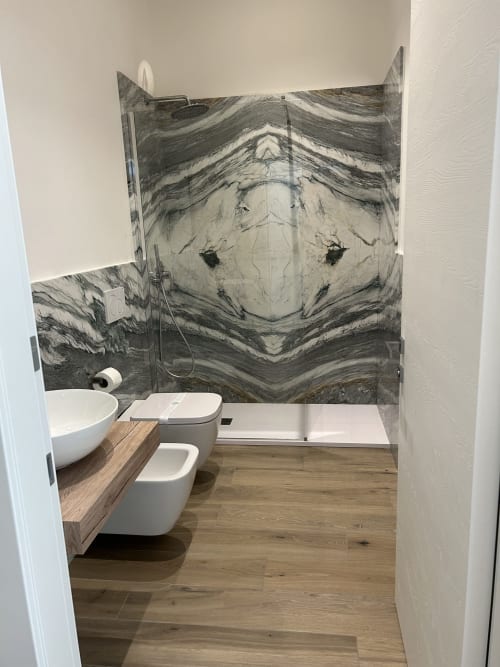 Bagno moderno a Breccia nel Mare con doccia effetto marmo, lavabo bianco sospeso e vanity in legno a Marina di Carrara