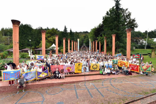 Large group gathering at CasaRosada with colorful flags and red columns in Vidracco, Italy