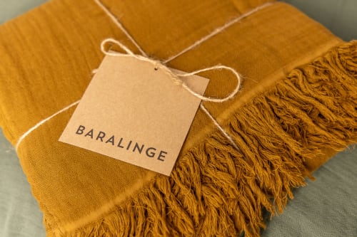 Golden mustard throw blanket with fringe and Baralinge brand tag at Le Prieuré Notre-Dame boutique hotel in Montfrin, France