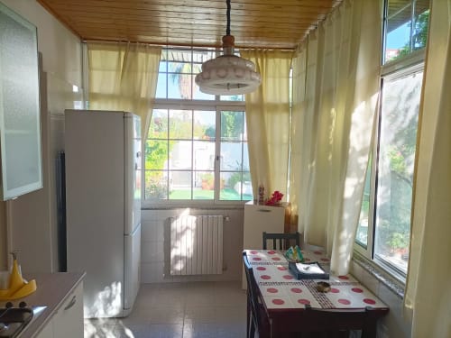 Cucina luminosa a Villa Newhouse, Bari con tavolo da pranzo, frigorifero moderno, lampada a sospensione e vista sul giardino