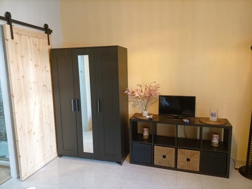 Camera da letto moderna a Newhouse Bari con guardaroba scuro, intrattenimento TV e porta stile barn