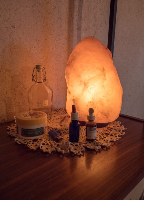Himalayan salt lamp glowing warmly beside wellness bottles and glass jar at CasaRosada B&B in Vidracco