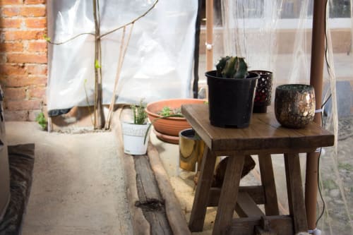 Cozy greenhouse space at CasaRosada with wooden table, potted cacti, terracotta pots, and brick walls in Vidracco