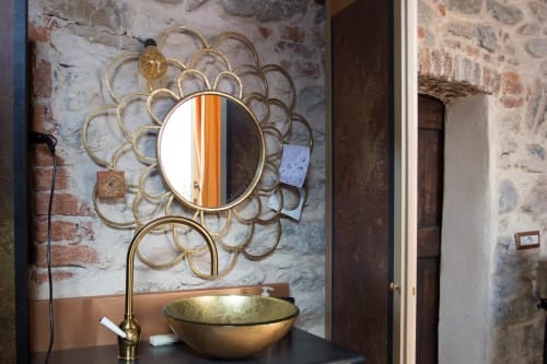 Decorative brass sunburst mirror above gold sink bowl in CasaRosada bathroom, Vidracco, Italy