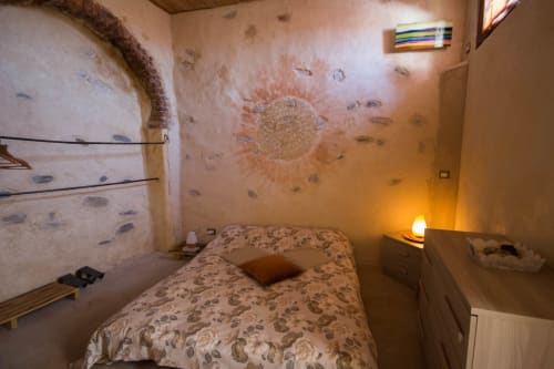 Cozy bedroom at CasaRosada B&B in Vidracco with patterned bedding, warm lamp, and rustic walls