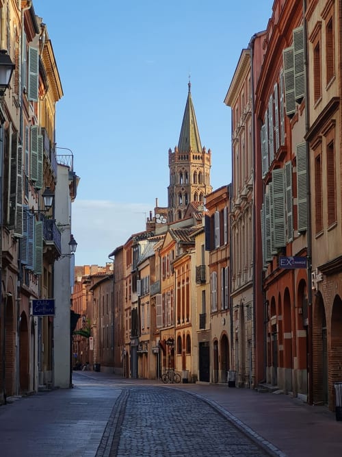 Charmante rue toulousaine aux bâtiments historiques en brique rouge et clocher d'église, près de l'hôtel Room In Toulouse