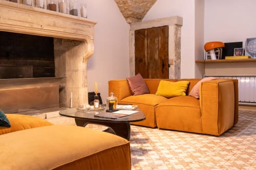 Maison d'hôtes gard avec piscine
 - Élégant salon avec canapés en velours orange, cheminée et porte en bois au Prieuré Notre-Dame à Montfrin, France.