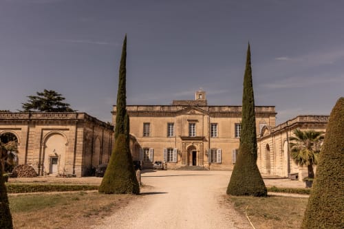 Le Prieuré Notre-Dame courtyard in Montfrin with stone mansion, cypress trees and manicured gardens