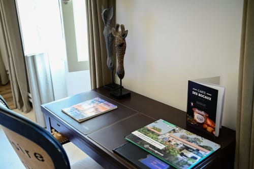 Desk with travel guides and giraffe sculpture in Pavillon Des Millésimes luxury room, Lussac