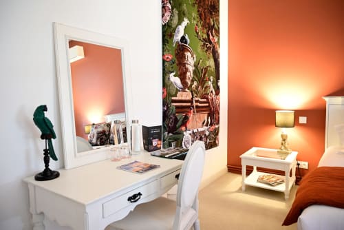 Elegant bedroom at Pavillon Des Millesimes with white vanity, ornate mirror, orange accent wall, and tropical decor