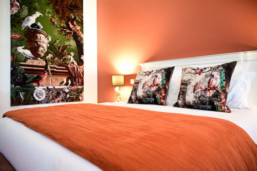 Elegant bedroom at Pavillon Des Millésimes SPA with orange accent wall, floral pillows, and botanical artwork