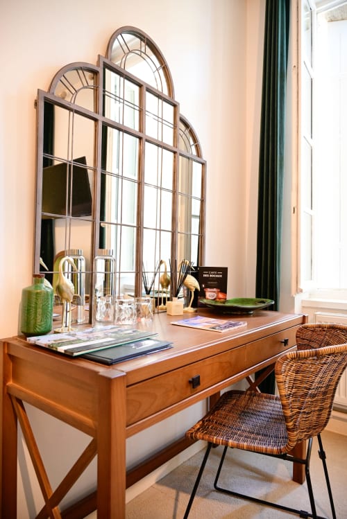 An elegant room at the Pavillon Des Millésimes featuring a wooden headboard, a palette of greens, a green armchair, and views of the pool and landscaped garden