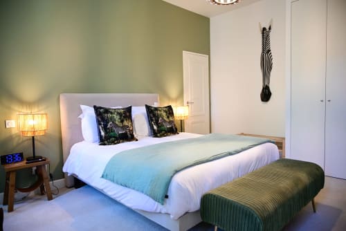 An elegant room at the Pavillon Des Millésimes featuring a wooden headboard, a palette of greens, a green armchair, and views of the pool and landscaped garden