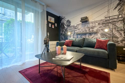 Cinema-themed studio apartment in Bordeaux with gray sofa, Hollywood sign wall mural, and city balcony view