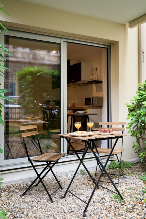 Outdoor seating area on patio of Wellkhome apartment in Bordeaux with small table, chairs, and sliding doors opening to
