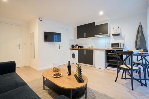 Modern studio apartment in Bordeaux with open-plan kitchen, dining area, and living space featuring black and wood