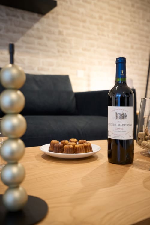 Château Martignas Graves wine bottle with pastries on wooden table in Bordeaux apartment