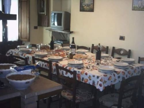 Sala da pranzo della villa Corte Pincione con tavolo apparecchiato, posate, bottiglie di vino e televisione a Montecarlo