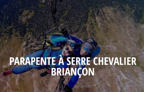Due paracadutisti in tuta blu sorvolano le montagne boscose vicino a Serre Chevalier Briançon