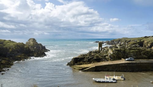 Petite crique côtière à La Maison D'olivier avec bateau amarré, falaises rocheuses et eaux turquoise en Bretagne