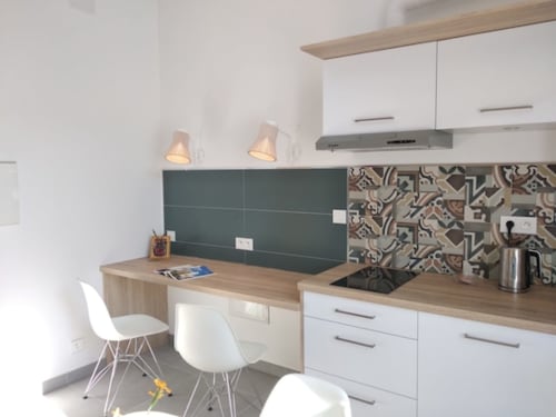 Cuisine moderne du gîte Clos des Moulins à Poitiers avec meubles blancs, plan de travail en bois et coin repas