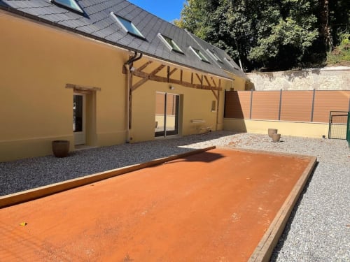 Cour avec court de tennis en terre et bâtisse jaune ocre aux Gites De Flaubert, Le Heron, France