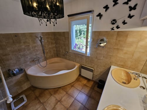 Modernes Badezimmer der Villa Sigahi mit geschwungener Badewanne, Waschbecken und gefliesten Wänden in La Croix Valmer