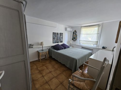 Helles Schlafzimmer in der Villa Sigahi in La Croix Valmer mit Queensize-Bett, Terrakottaboden und großem Fenster mit Poolblick