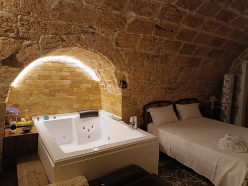 CorteLirice Paradiso Sottano 1 bedroom with Jacuzzi tub under stone arches and bed with white linens
