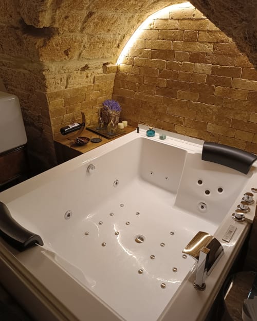 Luxury Jacuzzi bathtub in stone-walled bathroom at CorteLirice Paradiso, Sottano 1 apartment