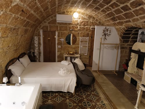 Cozy stone bedroom at CorteLirice Paradiso with bed, Jacuzzi tub, and rustic arched ceiling
