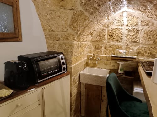 Cozy kitchenette in CorteLirice Paradiso Sottano 2 apartment with stone walls, toaster oven, sink, and dining area.