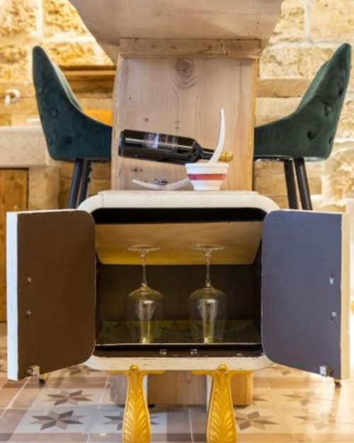 Bar table with green stools and open cabinet displaying wine glasses at CorteLirice Paradiso apartment Sottano 2, Italy