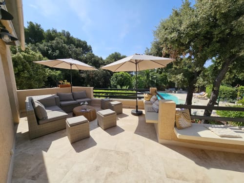 Sonnige Terrasse der Villa Sigahi mit Lounge-Bereichen, Sonnenschirmen und Poolblick über üppige Gärten in La Croix Valmer