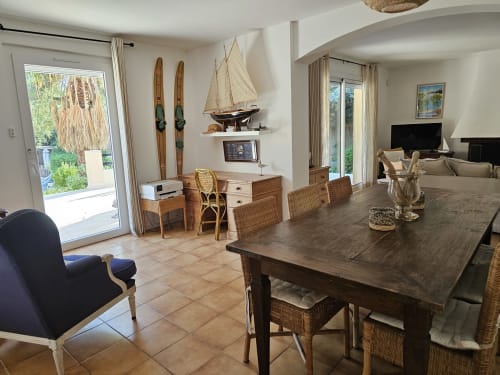 Geräumiger Speisebereich der Villa Sigahi mit Holztisch, Korbstühlen, maritimer Dekoration und Poolblick