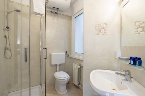 Bagno moderno dell'appartamento Re di Roma a Roma con doccia, toilette, lavandino e finestra con vista sulla città