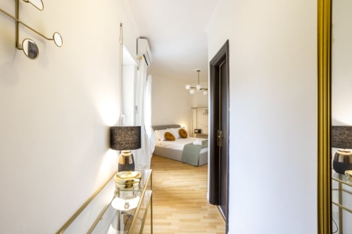 Corridoio moderno della suite al Re di Roma Hotel di Roma, che conduce alla camera da letto con pavimenti in legno e arredamento contemporaneo