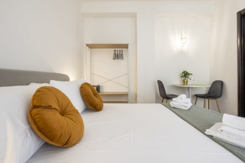 Camera moderna dell'hotel Re di Roma a Roma con cuscini giallo senape, biancheria bianca e zona relax con vista sulla città