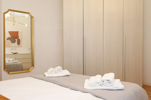 Camera da letto moderna dell'appartamento Re di Roma a Roma con specchio cornice dorata, asciugamani bianchi e guardaroba contemporaneo