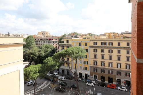 Vista della città dall'appartamento Re di Roma a Roma: strada con auto, alberi e edifici in tonalità ocra gialla